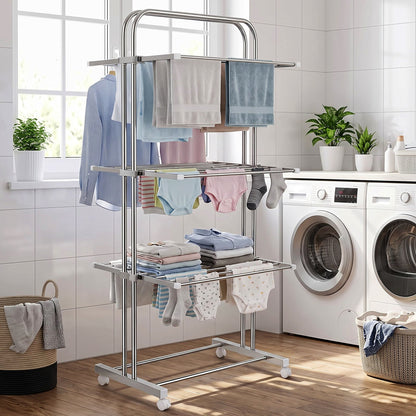 A stainless steel 3-layer clothes drying rack with various clothes and towels, positioned in a laundry room with washing