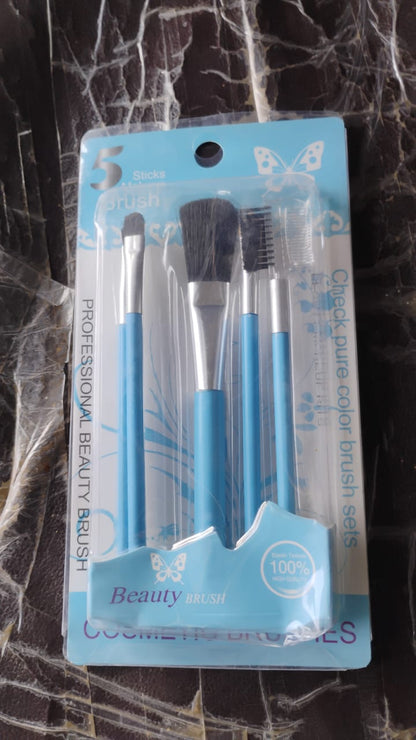 A clear plastic package containing five light blue makeup brushes, with text and butterfly graphics, on a dark background.
