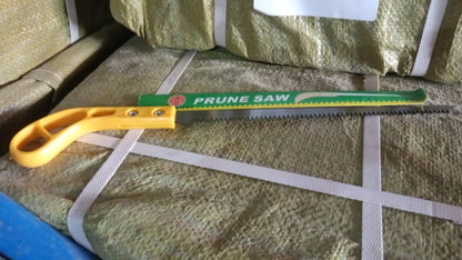 A yellow-handled pruning saw with a green blade cover lies on bundled packages.