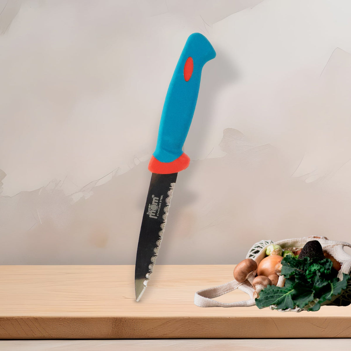 A blue and red handled paring knife stands upright on a light wooden surface, with a mesh bag of fresh vegetables in the
