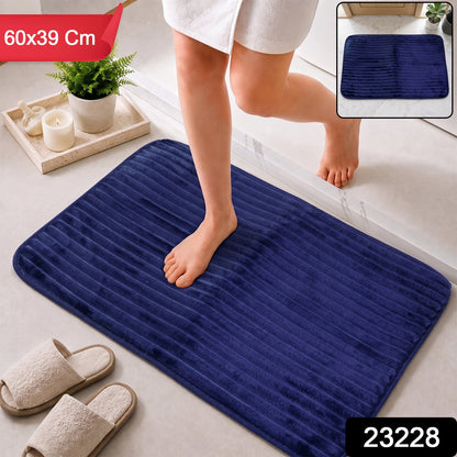 A person steps onto a navy blue ribbed memory foam bath mat, with dimensions 60x39 cm and product number 23228.