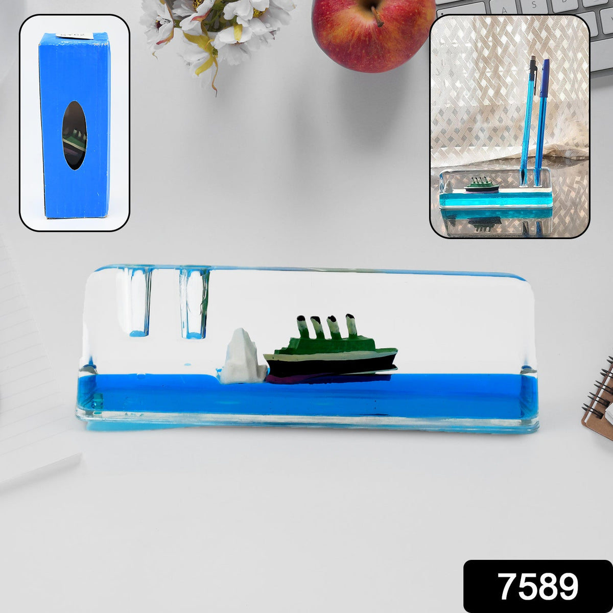 A clear rectangular liquid motion paperweight with a green ship and iceberg floats in blue liquid on a white desk.