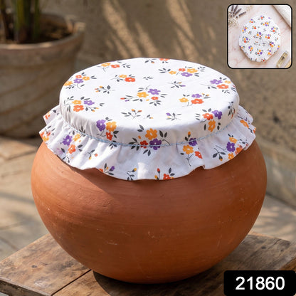 Close-up of a white fabric food cover with vibrant floral patterns on a clay pot.