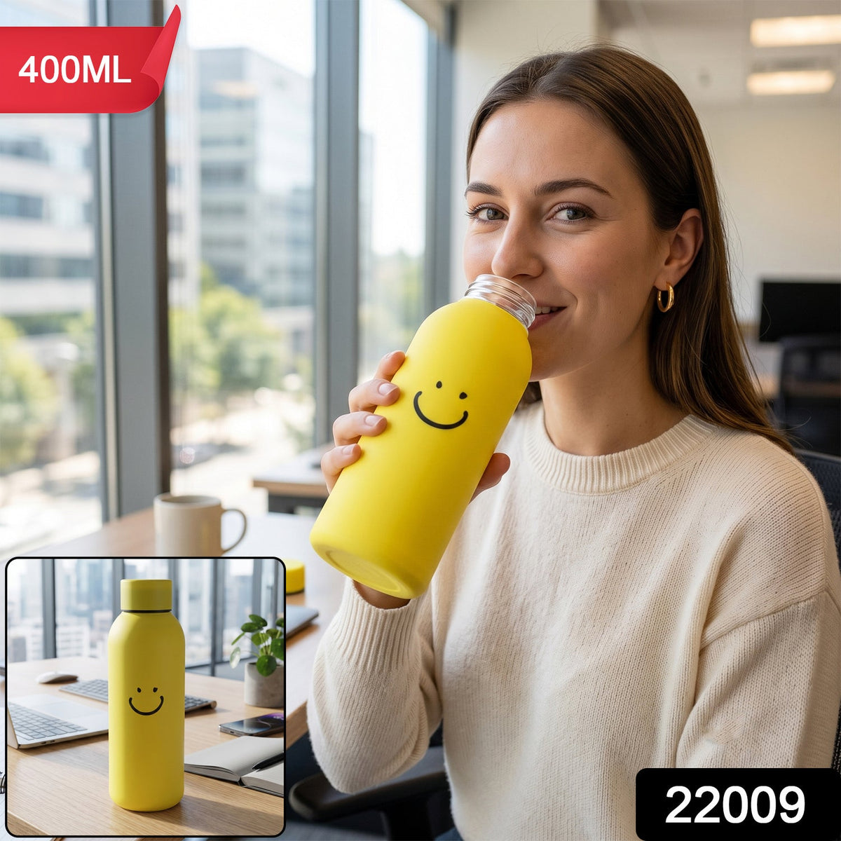 A woman in an office setting sips from a yellow glass water bottle with a smiley face on  
bottle.