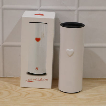 A white thermal tumbler with a heart detail stands next to its product box, which also features a heart design.