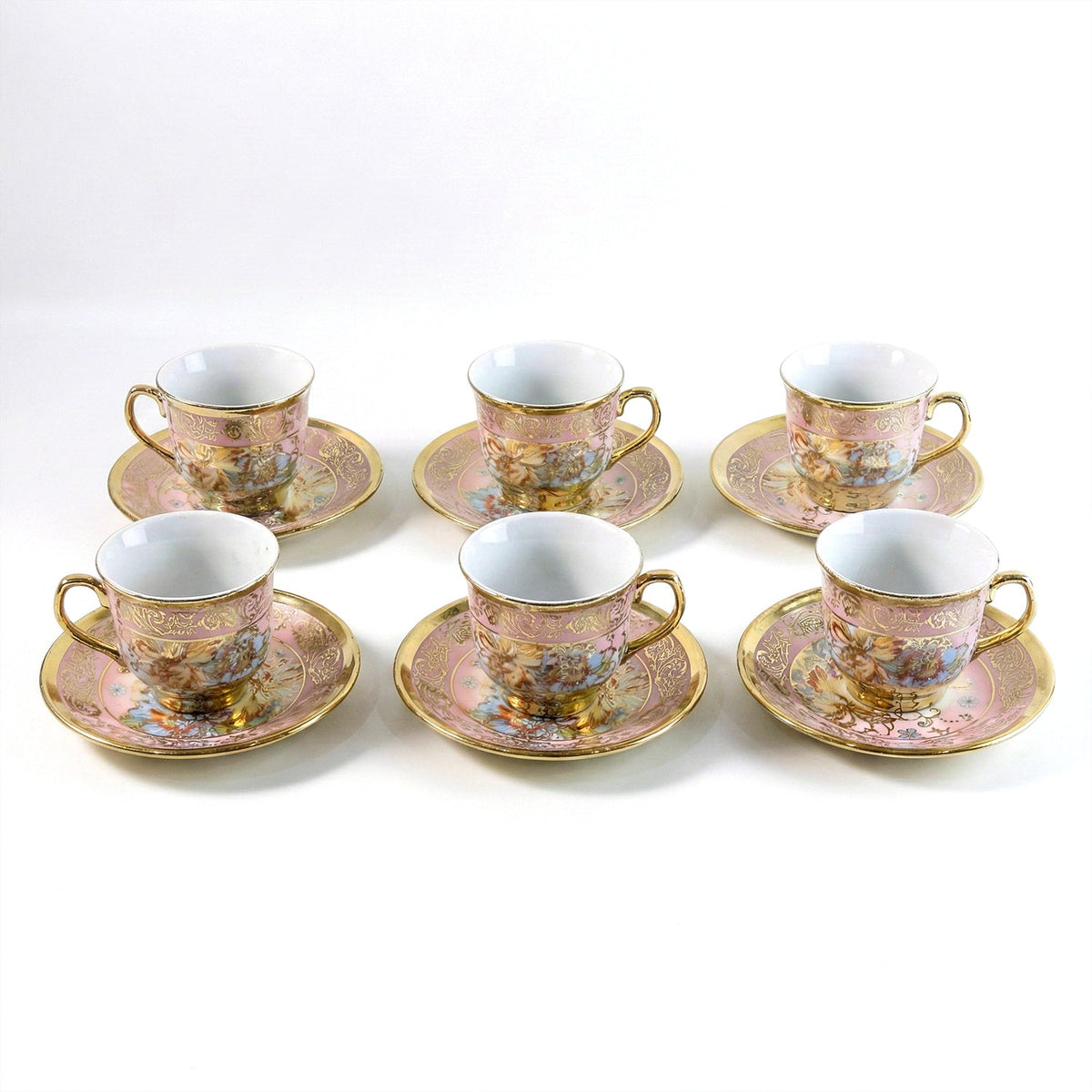 Six pink and gold floral porcelain teacups and saucers with gold rims and handles are neatly arranged on a white surface.